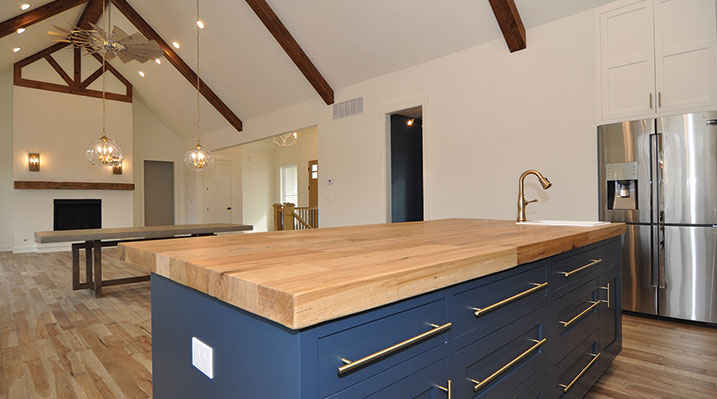 ICH Builders Dublin Ohio residence custom build close up of kitchen island with wood countertop looking out towards dining area