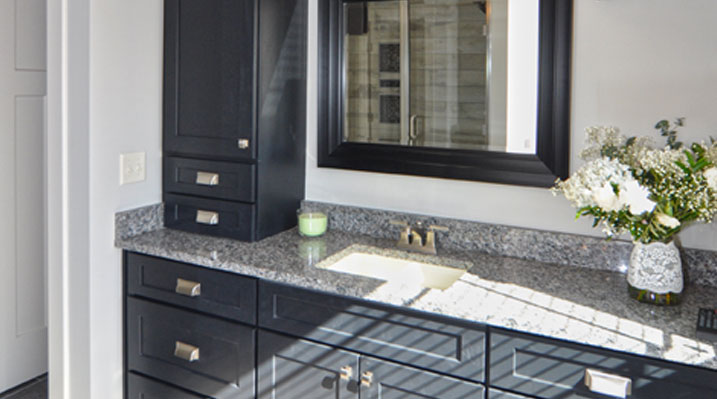 slider image of Berlin Ohio residence custom build view of bathroom vanity with dark wooden cabinets and drawers and gold fixtures