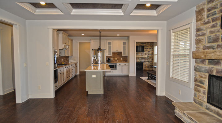 ICH Builders Berlin Ohio residence custom build view from main room looking towards kitchen showcasing the stone fireplace and wooden floors