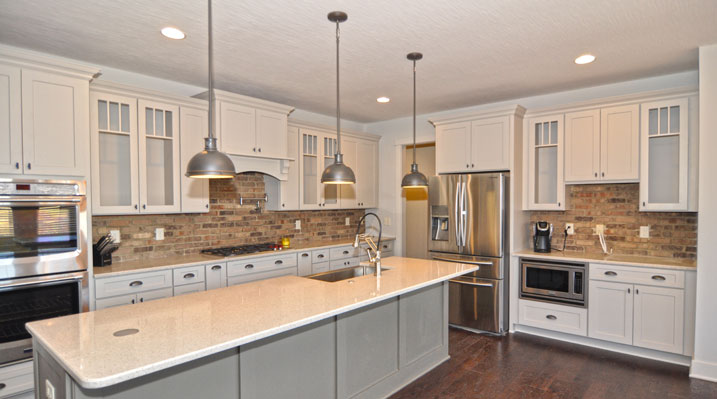 ICH Builders Berlin Ohio residence custom build kitchen showing island, cabinets, brick backsplash and industrial ceiling lighting