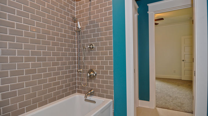 Iulianelli Custom Homes Lithopolis Ohio residence custom build second bathroom bathtub with tan colored wall tiling and gold faucet and shower fixtures