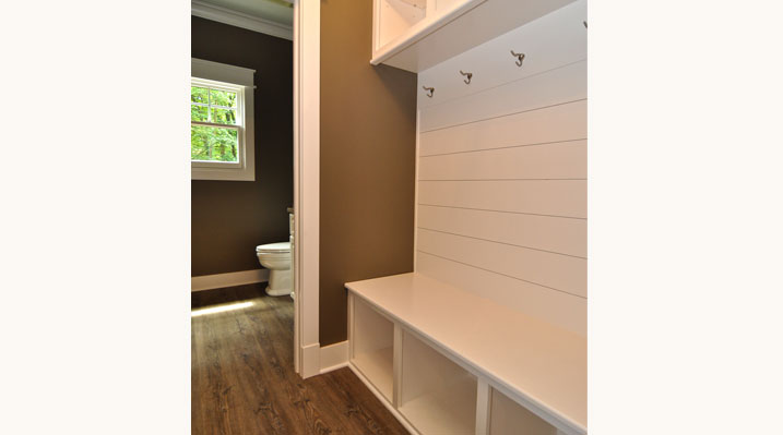 ICH Lithopolis Ohio residence custom build mudroom with white walls, clothing hooks, and storage cubbies underneath the bench