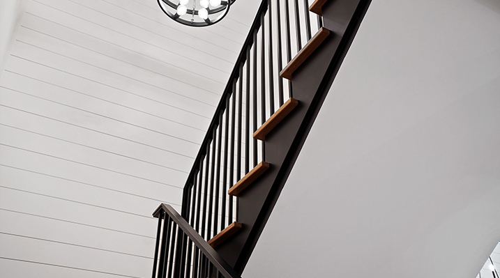 ICH Builders Canal Winchester Ohio residence custom build close up of modern staircase railing system with black metal vertical balusters and wood stair treads