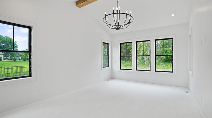 ICH Builders Canal Winchester Ohio residence custom build bedroom with white floors and ceiling, black framed windows, and hanging black 10-Light Chandelier