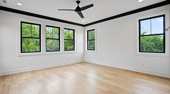 ICH Builders Canal Winchester Ohio residence custom build bedroom with white walls, black framed windows, wooden floors, and black 3 blade modern ceiling fan