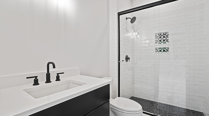 ICH Builders Canal Winchester Ohio residence custom build bedroom bathroom with black vanity with white countertop and black fixtures with standing shower with sliding glass door in background